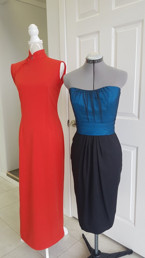 Two finished evening dresses on dress forms — a red sleeveless gown and a blue-and-black strapless dress