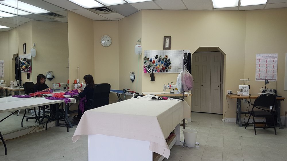 Inside New Stitch Tailor's workshop in La Perle, Edmonton — sewing machines, cutting tables and a wall of thread spools at work